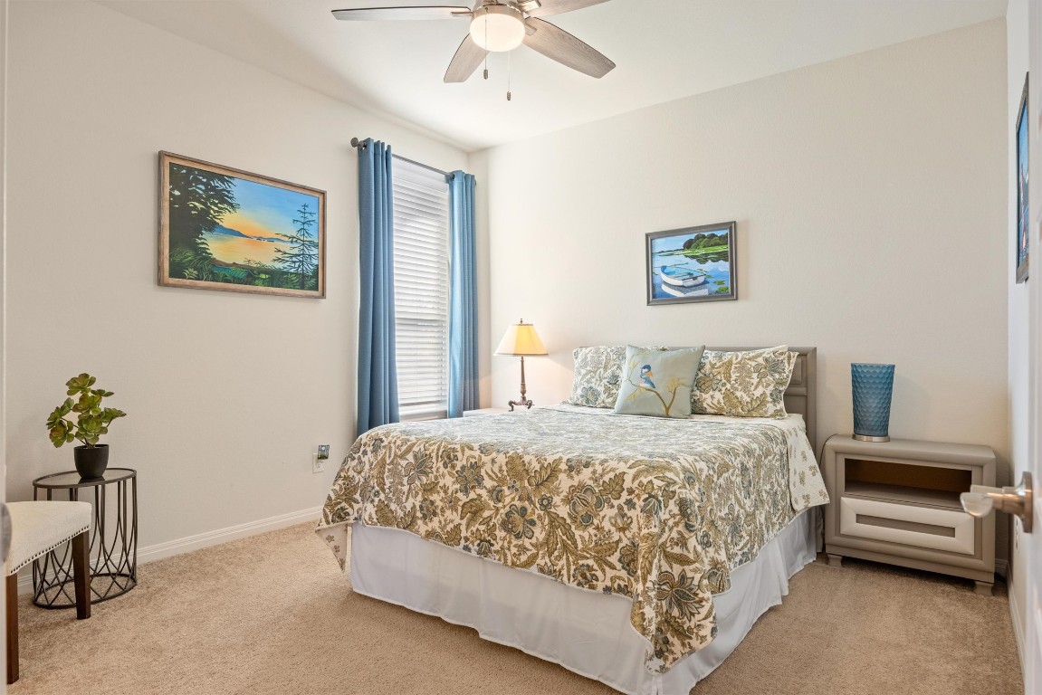 210 Raptor Beak Way Cedar Creek, TX 78612 - Photo 21 of 36 a bedroom with a bed and a chandelier