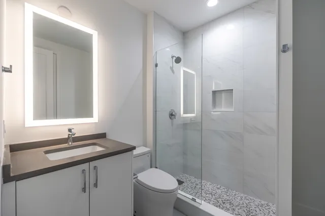 a bathroom with a sink a toilet and shower