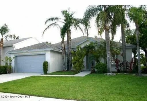 a view of a house with a yard and palm trees