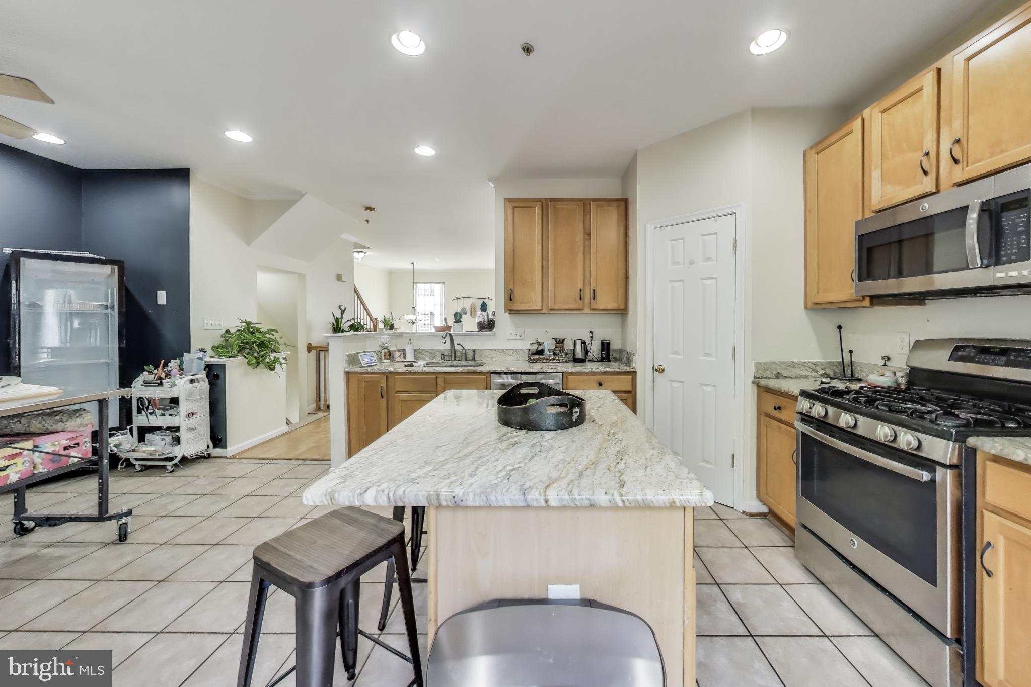 839 Patuxent Run Circle Odenton, MD 21113 - Photo 6 of 28 a kitchen with kitchen island granite countertop a stove a sink a refrigerator and chairs