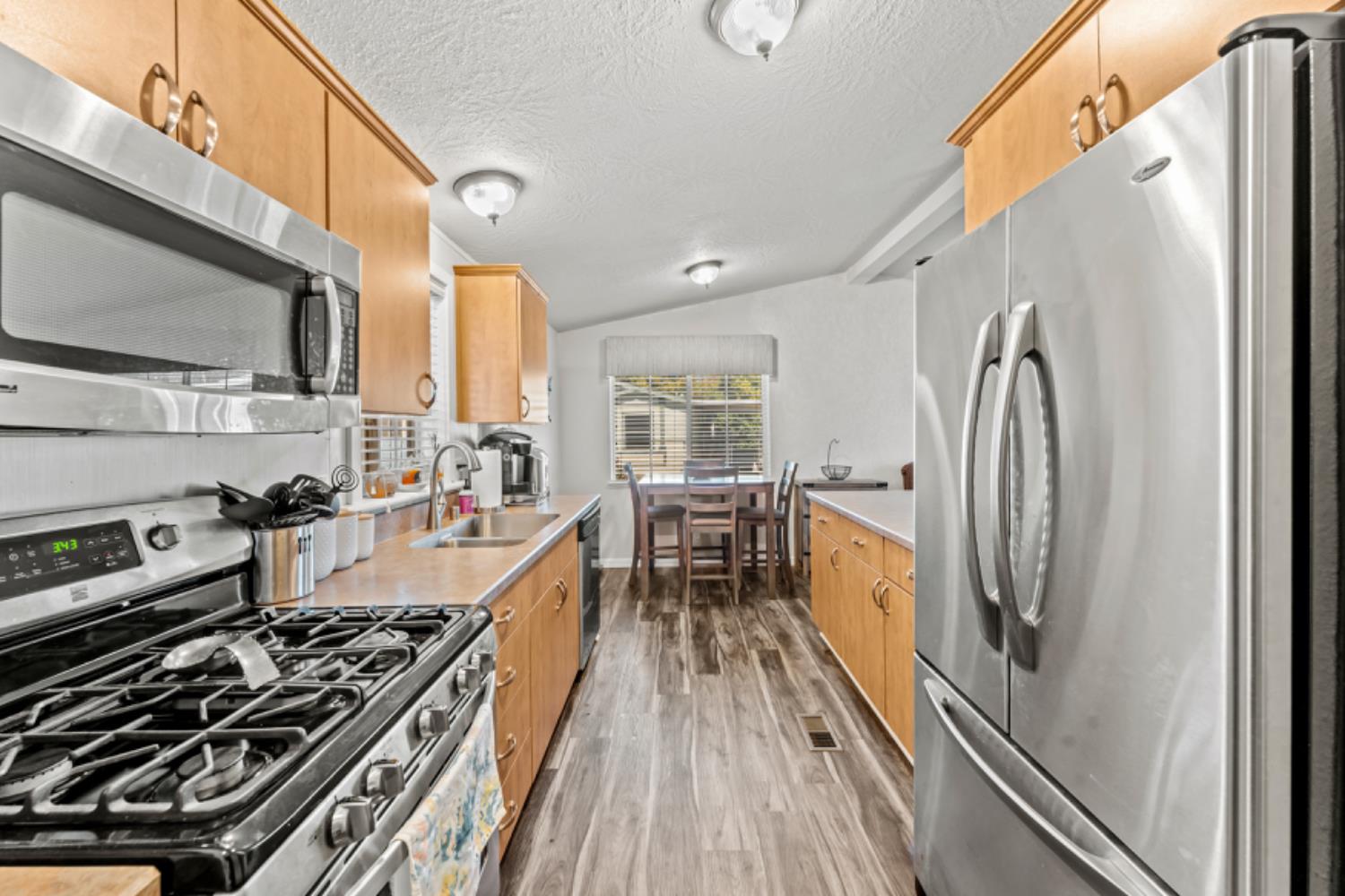 a kitchen with stainless steel appliances granite countertop a stove top oven a sink dishwasher a refrigerator and cabinets with wooden floor