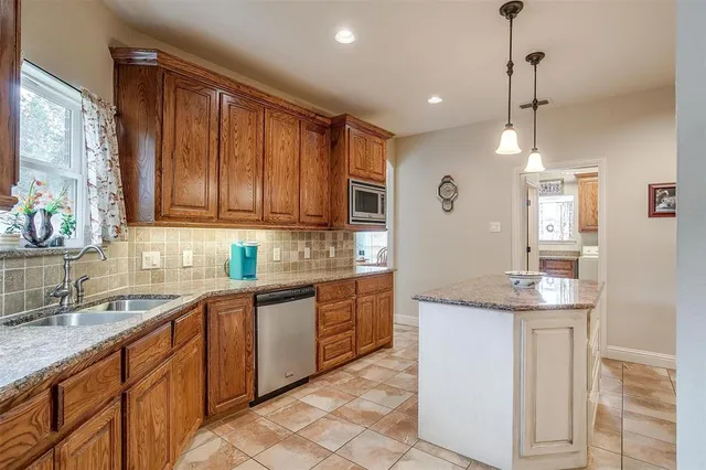 a kitchen with kitchen island granite countertop a sink window and cabinets