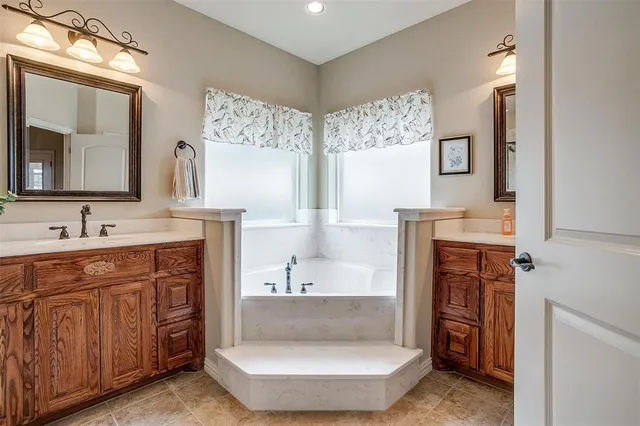 a spacious bathroom with a double vanity sink mirror and bathtub