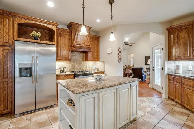 a kitchen with stainless steel appliances granite countertop a refrigerator a sink a stove and a wooden cabinets
