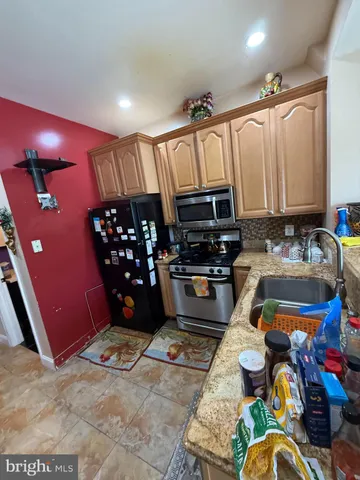 a kitchen with granite countertop a stove a sink and a refrigerator