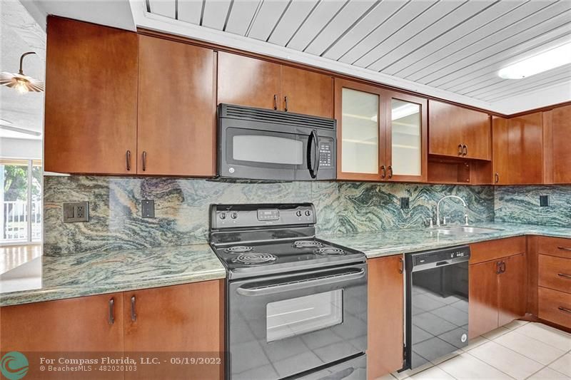 a kitchen with stainless steel appliances granite countertop a sink window and cabinets