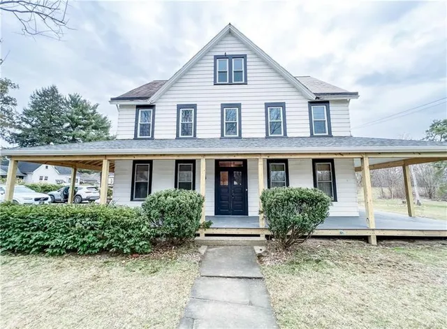 a front view of a house with a yard and potted plants
