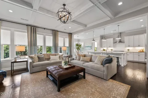 a living room with furniture kitchen view and a chandelier
