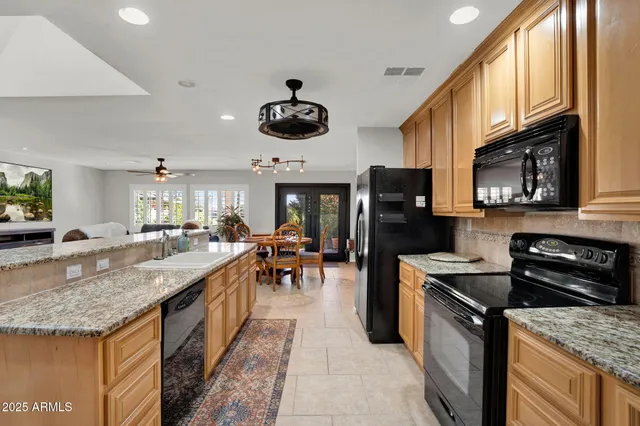 a kitchen with granite countertop kitchen island stainless steel appliances a dining table and chairs