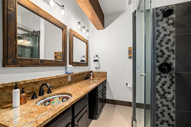 a bathroom with a granite countertop sink a mirror and shower