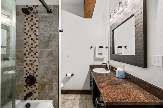 a bathroom with a granite countertop sink a mirror and shower