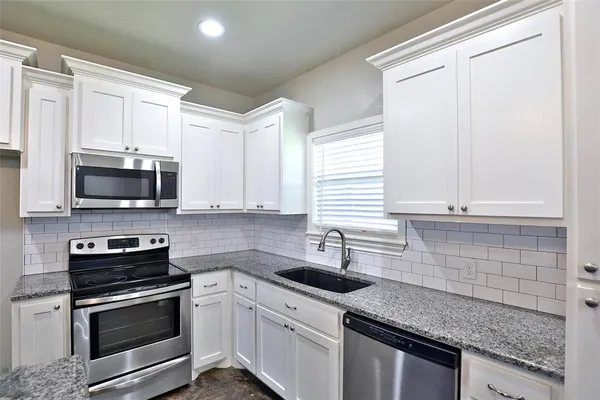 a kitchen with stainless steel appliances granite countertop a sink stove a microwave and cabinets