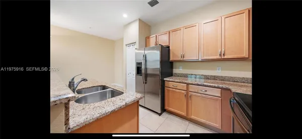 a kitchen with granite countertop a refrigerator sink and stove