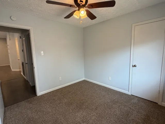an empty room with closet and a chandelier fan