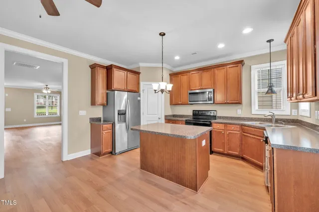 a kitchen with stainless steel appliances granite countertop a refrigerator a sink dishwasher a stove and white countertops with wooden floor