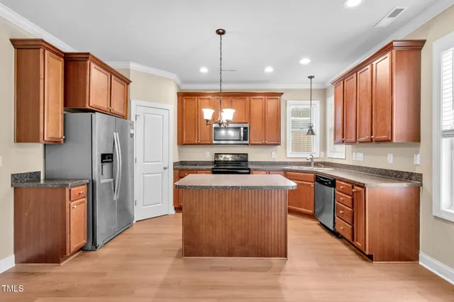 a kitchen with stainless steel appliances granite countertop a stove a sink a refrigerator a center island and a window