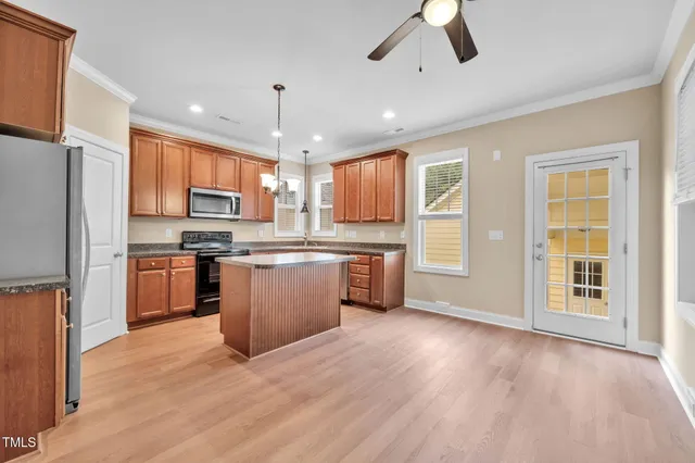 a kitchen with stainless steel appliances granite countertop a refrigerator a sink dishwasher a stove and a refrigerator with wooden floor