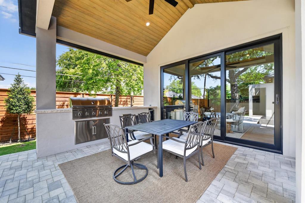 11028 Edgemere Road Dallas, TX 75230 - Photo 35 of 40 Covered patio with a high vaulted wood-finish ceiling, featuring an integrated stainless steel grill and a built-in countertop