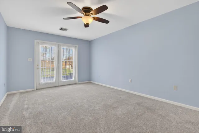 an empty room with windows and fan