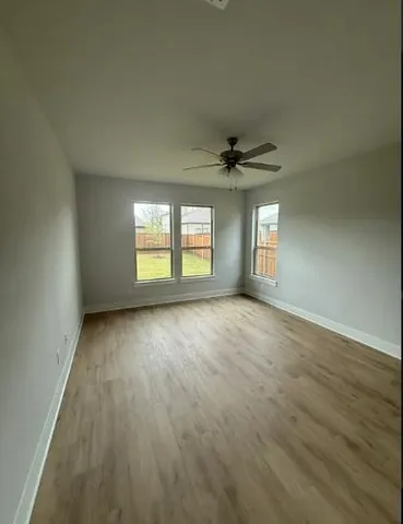 an empty room with wooden floor and windows