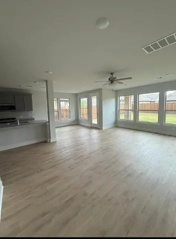 a view of an empty room with window and wooden floor