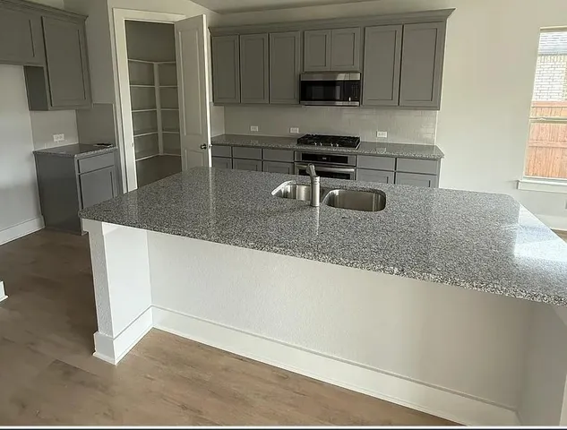 a kitchen with stainless steel appliances granite countertop a sink a stove and a microwave