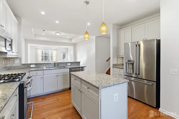 a kitchen with stainless steel appliances granite countertop a refrigerator a sink and a stove