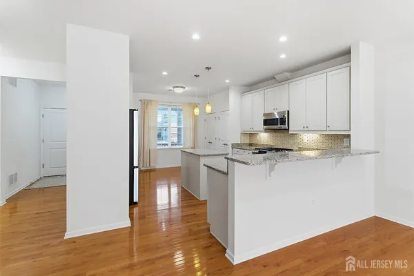 a kitchen with stainless steel appliances granite countertop a refrigerator a sink dishwasher and a oven with white cabinets