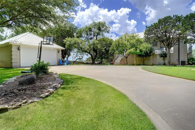 a backyard of a house with plants and large tree
