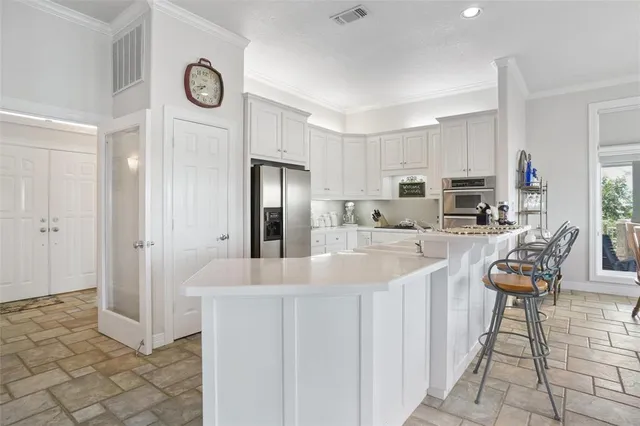 a large kitchen with stainless steel appliances granite countertop a refrigerator and a sink