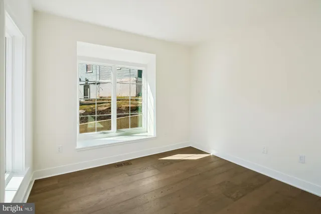 an empty room with wooden floor ceiling fan and windows