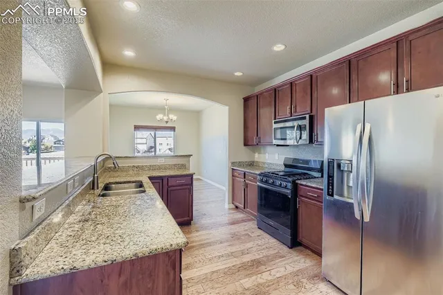 a kitchen with stainless steel appliances granite countertop sink stove refrigerator and cabinets