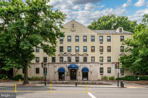 a front view of a building with lot of trees