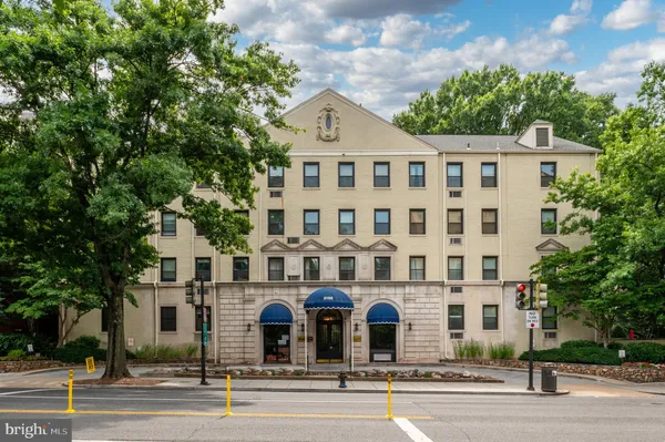 a front view of a building with lot of trees