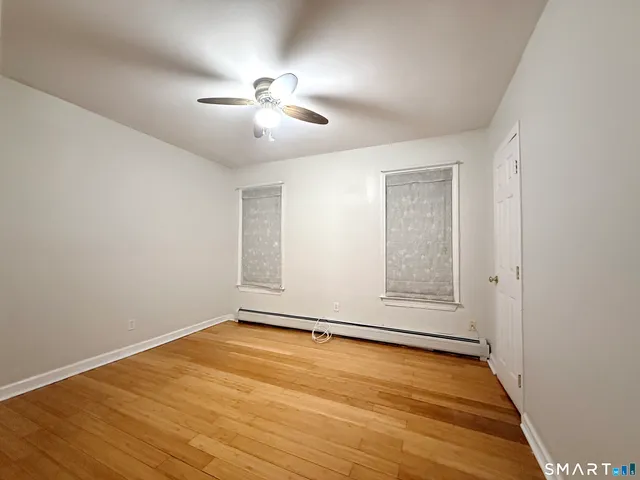 an empty room with wooden floor fan and windows