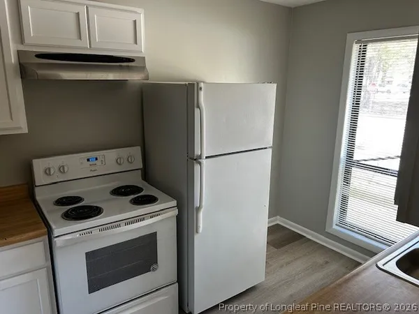 a kitchen with a refrigerator stove and white cabinets