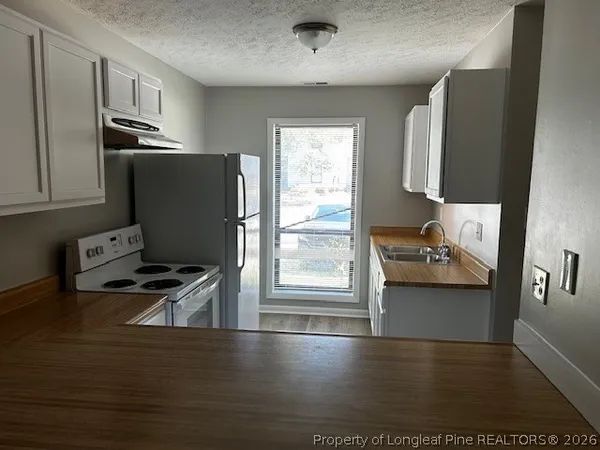 a kitchen with granite countertop a refrigerator stove and sink