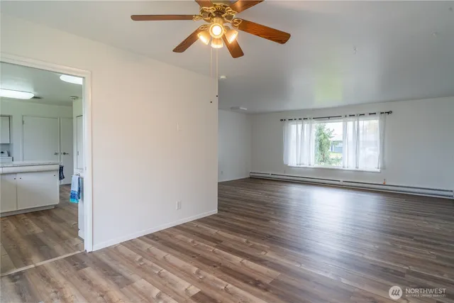 a view of an empty room with window and wooden floor