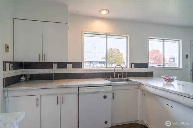 a kitchen with granite countertop a sink white cabinets and a window