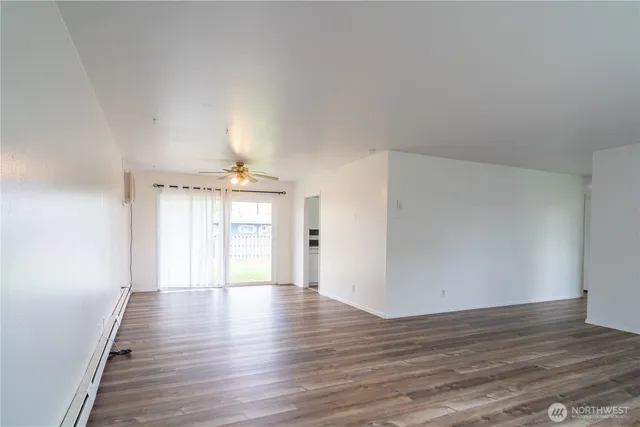 a view of an empty room with wooden floor and a window
