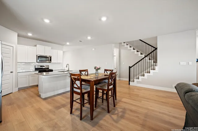 a kitchen with white cabinets stainless steel appliances and dining table