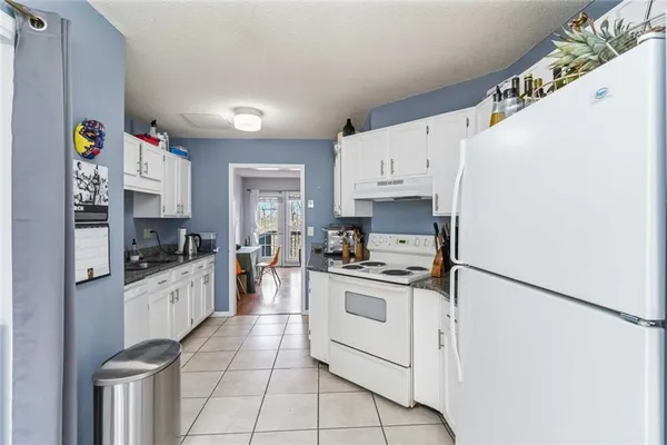 a kitchen with stainless steel appliances a refrigerator sink stove and white cabinets