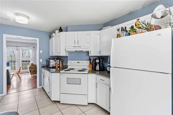 a view of kitchen with refrigerator and white cabinets