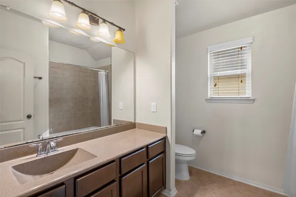 a bathroom with a granite countertop sink a toilet and a mirror