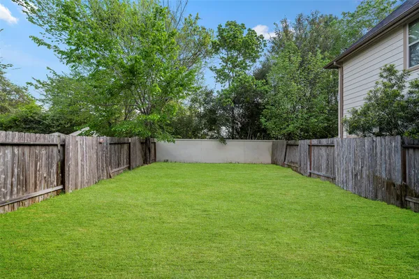 a view of a backyard with a fence and trees