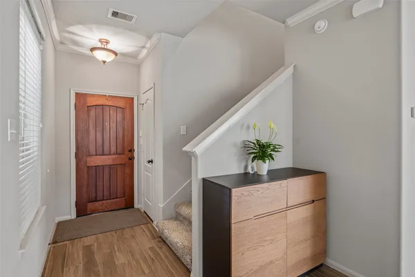 a hallway with front door wooden floor and a chandelier