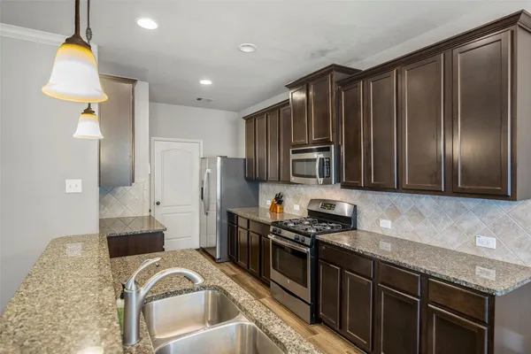 a kitchen with stainless steel appliances granite countertop a stove a sink and a refrigerator