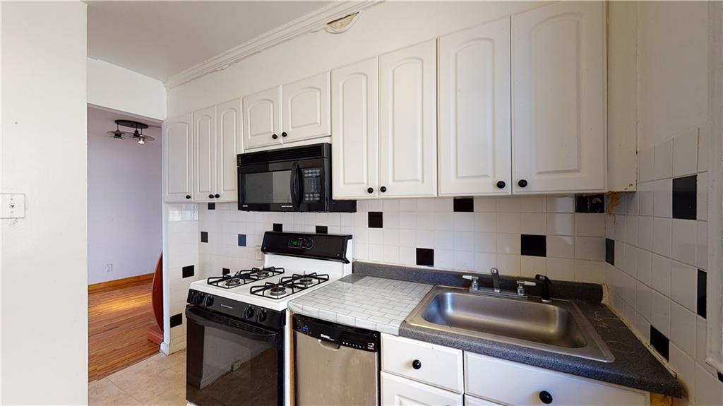 150 West End Avenue, Unit 5H Brooklyn, NY 11235 - Photo 5 of 17 a kitchen with granite countertop a sink stove and white cabinets