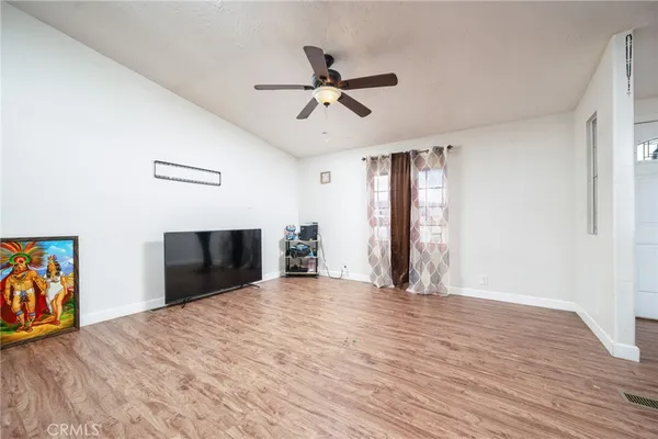 a view of empty room with wooden floor and ceiling fan