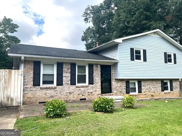 a view of a brick house with a large windows plants and large trees